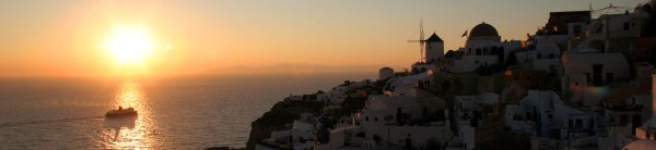 Ferry passing in front of Oia in Santorini, during the sunset